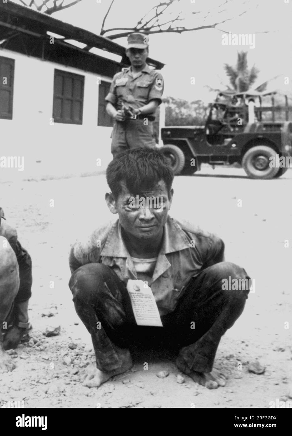 SAIGON, VIETNAM - febbraio 1968 - Un giovane combattente Vietcong, pesantemente sorvegliato, attende gli interrogatori dopo la cattura negli attacchi alla capitale Foto Stock