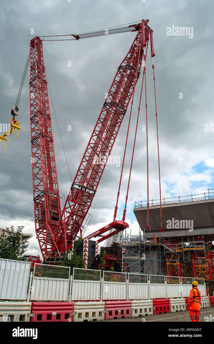 Harefield, Regno Unito. 3 agosto 2023. La costruzione da parte di Align JV prosegue sul viadotto HS2 della Colne Valley per la ferrovia ad alta velocità. Moorhall Road (nella foto) a Harefield, nel borgo londinese di Hillingdon è attualmente chiusa al traffico in quanto le strutture di supporto temporanee vengono messe in atto dall'altra parte della strada sotto i segmenti del viadotto che vengono assemblati da una gru cingolata. Il viadotto della Colne Valley attraverserà Moorhall Road tra il lago Korda e il lago Savay, appena a sud del Grand Union Canal. L'Autorità per le infrastrutture e i progetti, ha collocato il progetto HS2 da miliardi di sterline tra Londra e Foto Stock