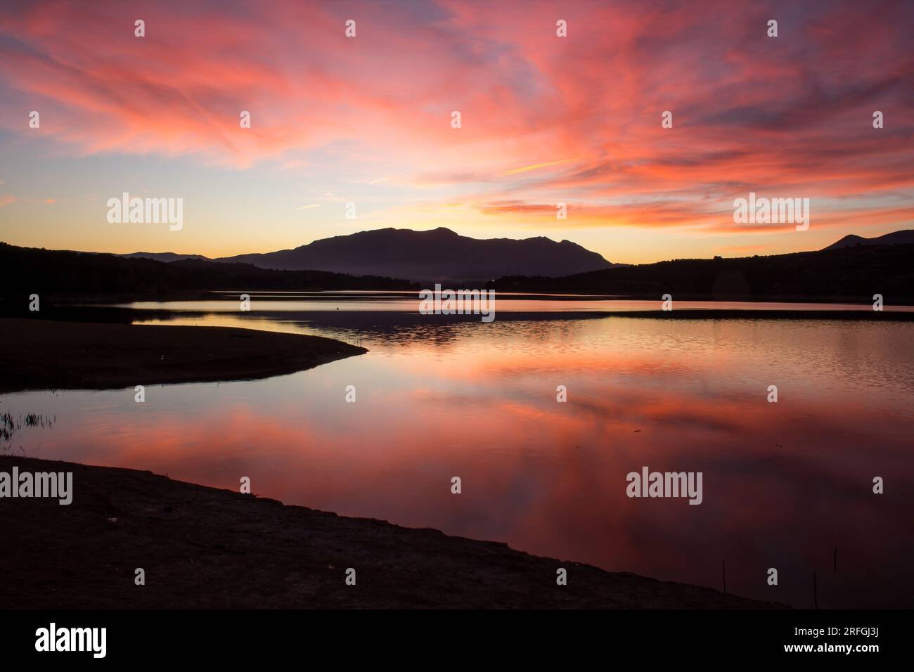 Tramonto nel bacino idrico di Beniarrés con riflessi rossi nell'acqua Foto Stock