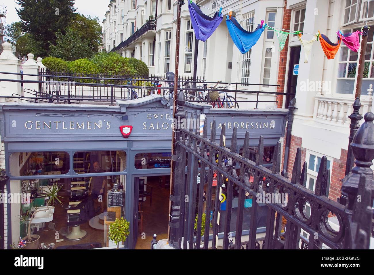 Inghilterra, East Sussex, Brighton, Hove, Western Road, Ingresso al barbiere sotterraneo di Gwydr decorato con pantaloni dai colori mutli. Foto Stock