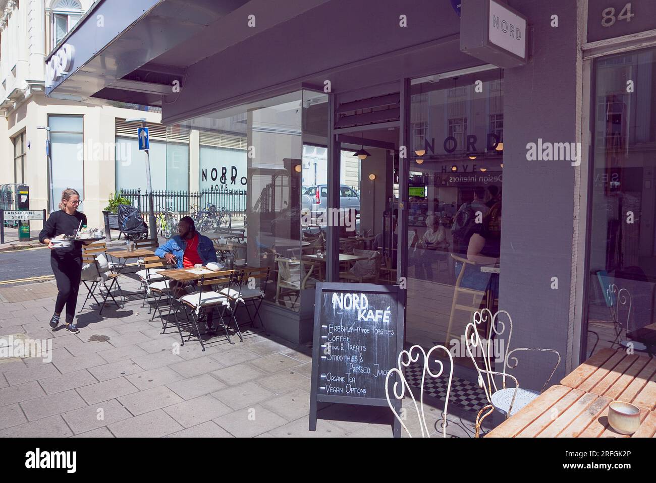 Inghilterra, East Sussex, Brighton, Hove, Western Road, Cameriera che puliva il tavolo fuori dal Nord Cafe. Foto Stock