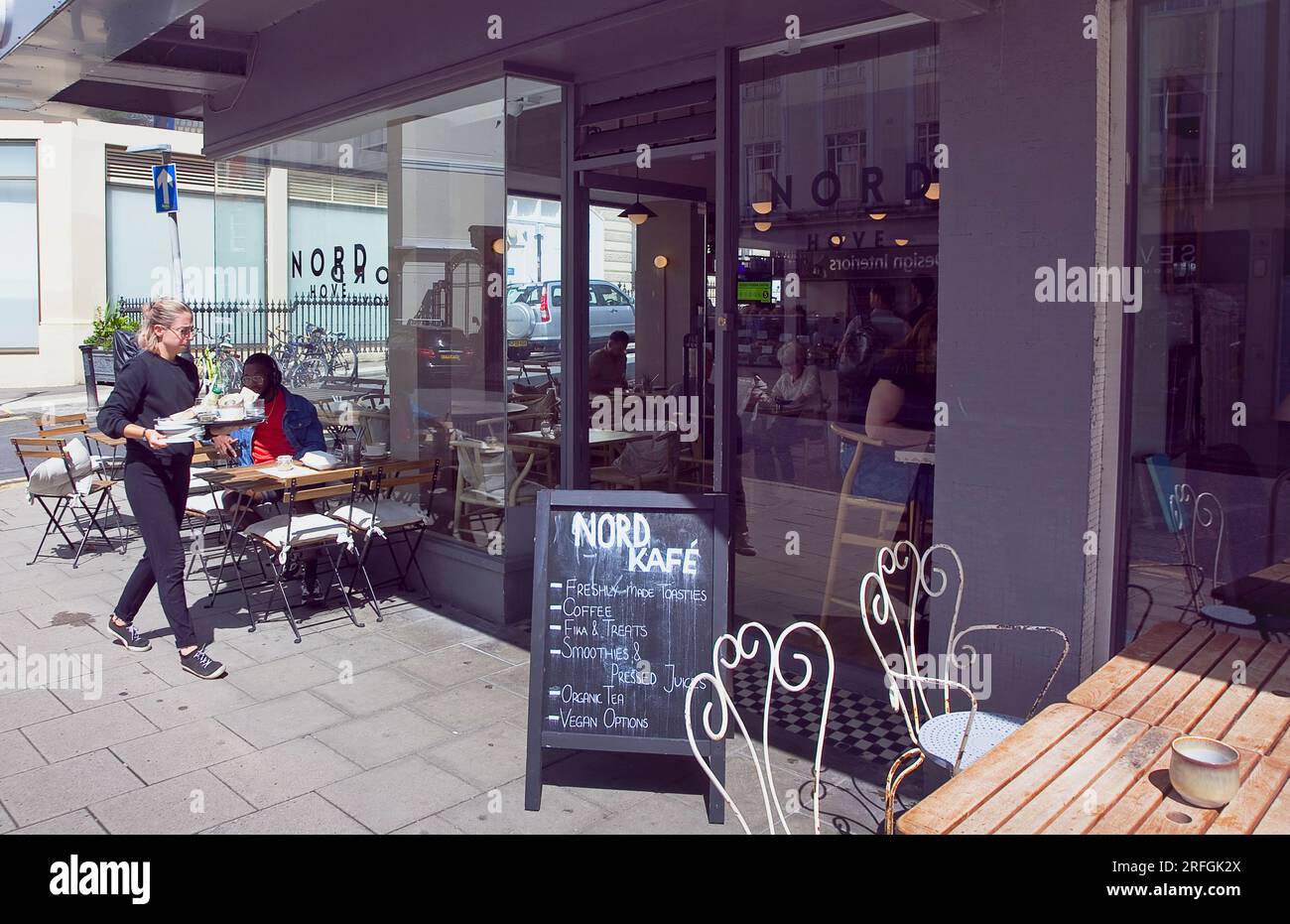 Inghilterra, East Sussex, Brighton, Hove, Western Road, Cameriera che puliva il tavolo fuori dal Nord Cafe. Foto Stock