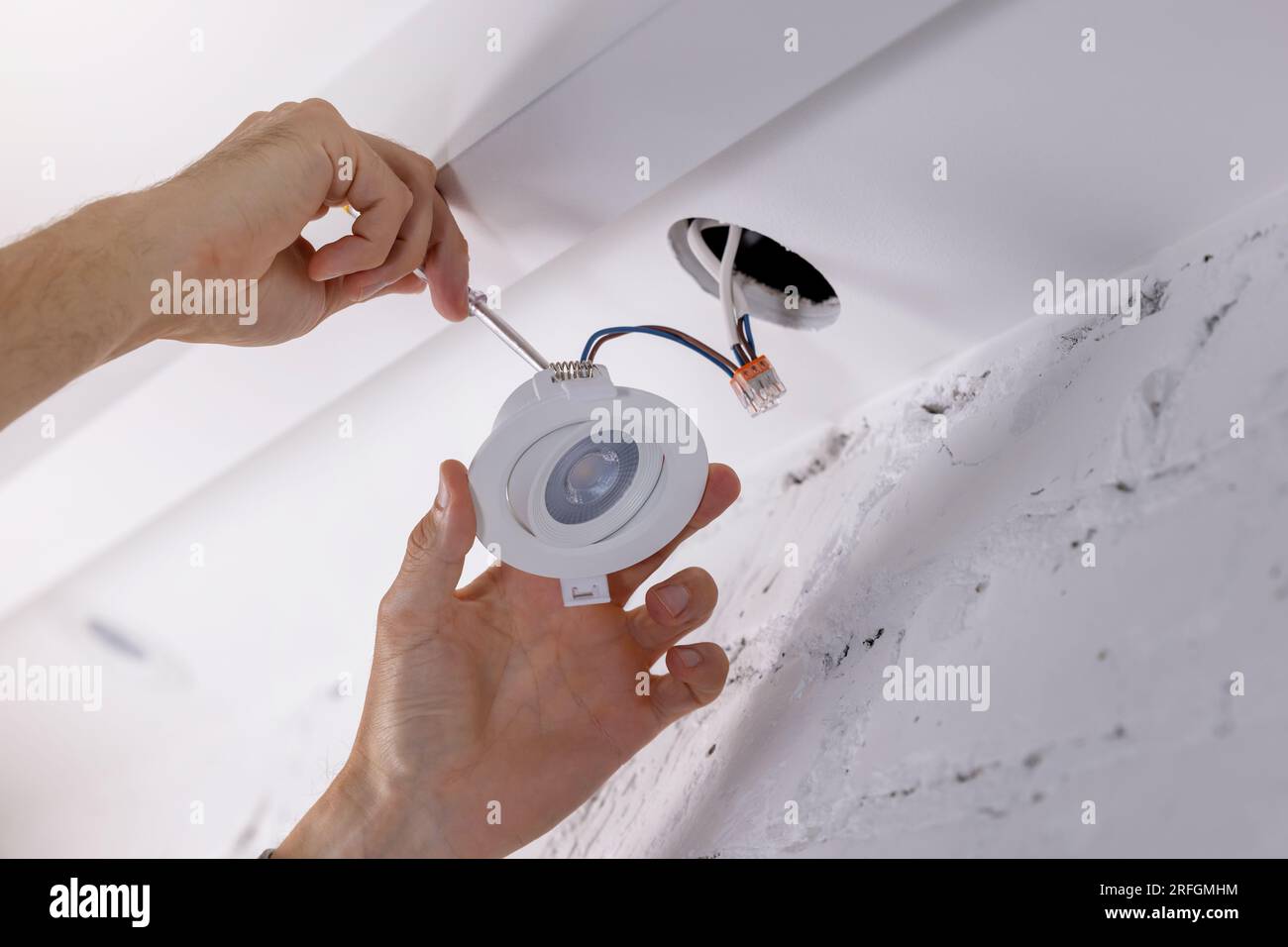 elettricista che installa la lampada a incasso nel soffitto a cartongesso. illuminazione a led Foto Stock