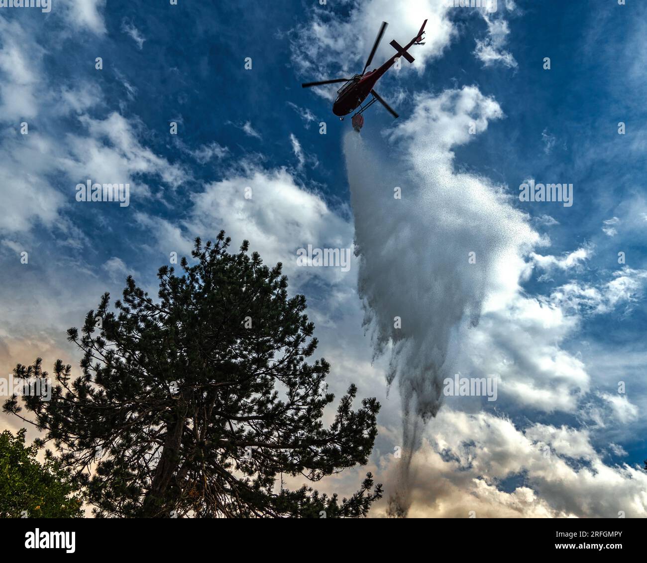 Scena drammatica con fiamme e fumo provenienti da un incendio boschivo. L'elicottero della protezione civile combatte le fiamme con l'acqua Monte Morrone, Parco Nazionale della Maiella Foto Stock