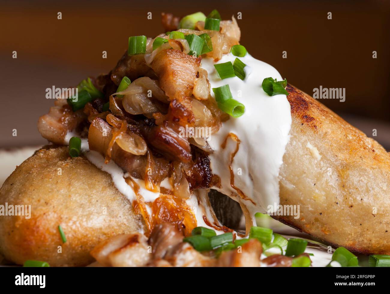 Piatto tradizionale lituano servito con panna acida e pancetta fritta, zeppelin a base di patate grattugiate con carne macinata Foto Stock