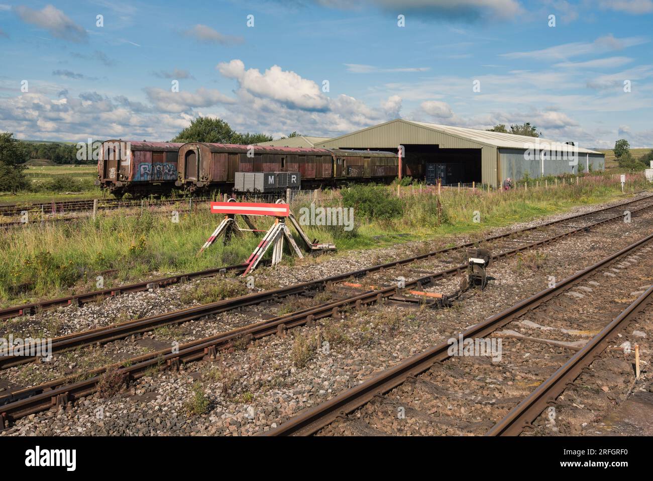 Capannone e vecchie carrozze ferroviarie a Hellifield, North Yorkshire, viste dalla fine del binario della stazione Foto Stock