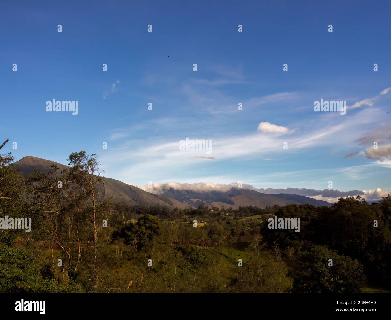 Un cielo per lo più limpido e nuvole soffici nel pomeriggio, sulle fattorie delle montagne andine orientali della Colombia centrale. Foto Stock