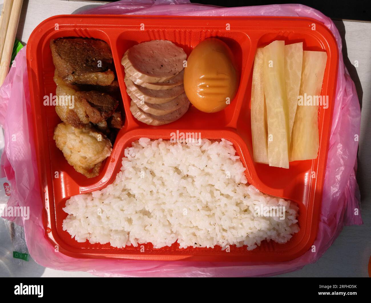 Una ciotola di riso con fette di anatra salate, salsiccia rossa, uova brasate e kimchi di ravanelli sul treno da Pyongyang a Dandong Foto Stock