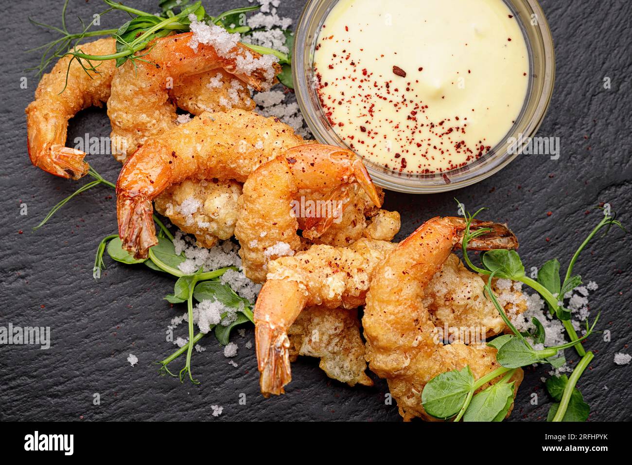 Gamberetti fritti in pastella con salsa, su ardesia nera, su fondo scuro Foto Stock