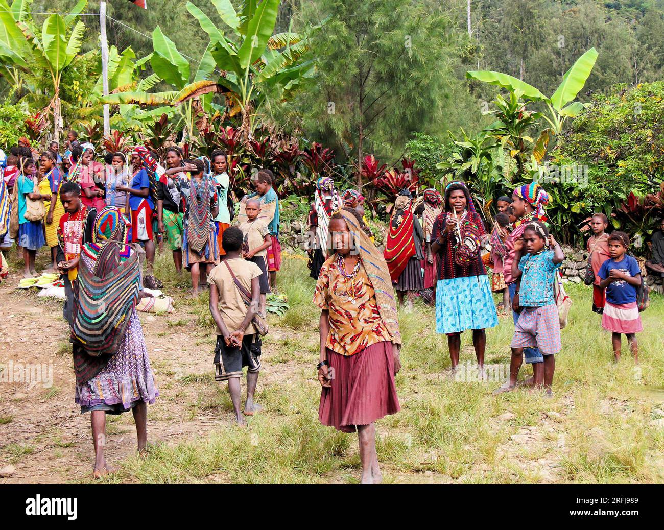 Un gruppo di papuani indonesiani in un piccolo mercato, dove vengono venduti prodotti come yam e oggetti di artigianato come perline, reti da trasporto come sacchetti, ecc. Foto Stock