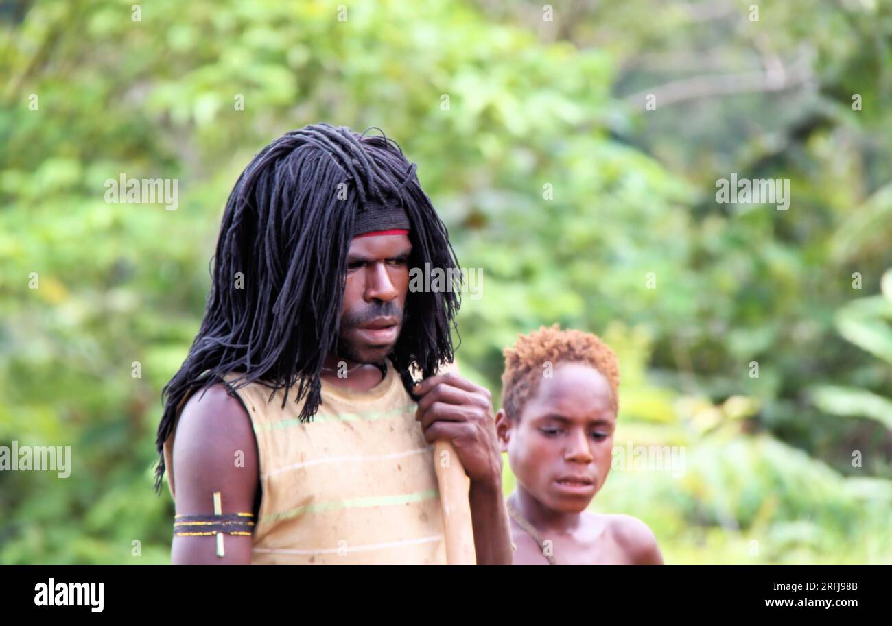 L'uomo con i dreadlock e il ragazzo con i capelli rossastri si trovano accanto alle giungle negli altopiani di Papua, Indonesia. Foto Stock