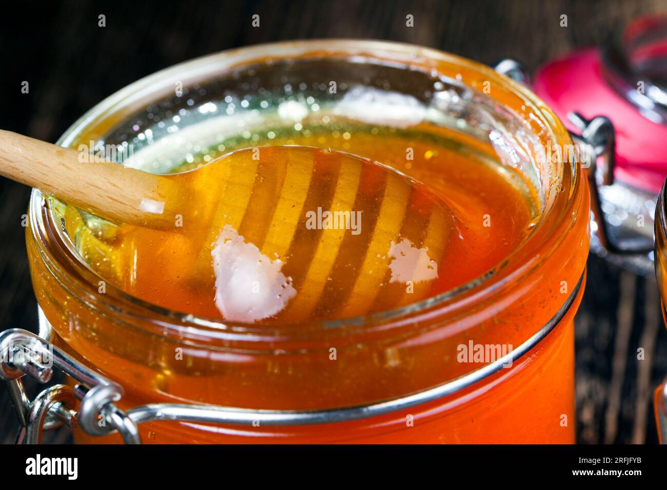 immerso nel miele, realizzato appositamente con cucchiaio grezzo fatto in casa in legno, miele di api dolci e cucchiaio di legno che consente di trasferire e versare il miele senza dr Foto Stock