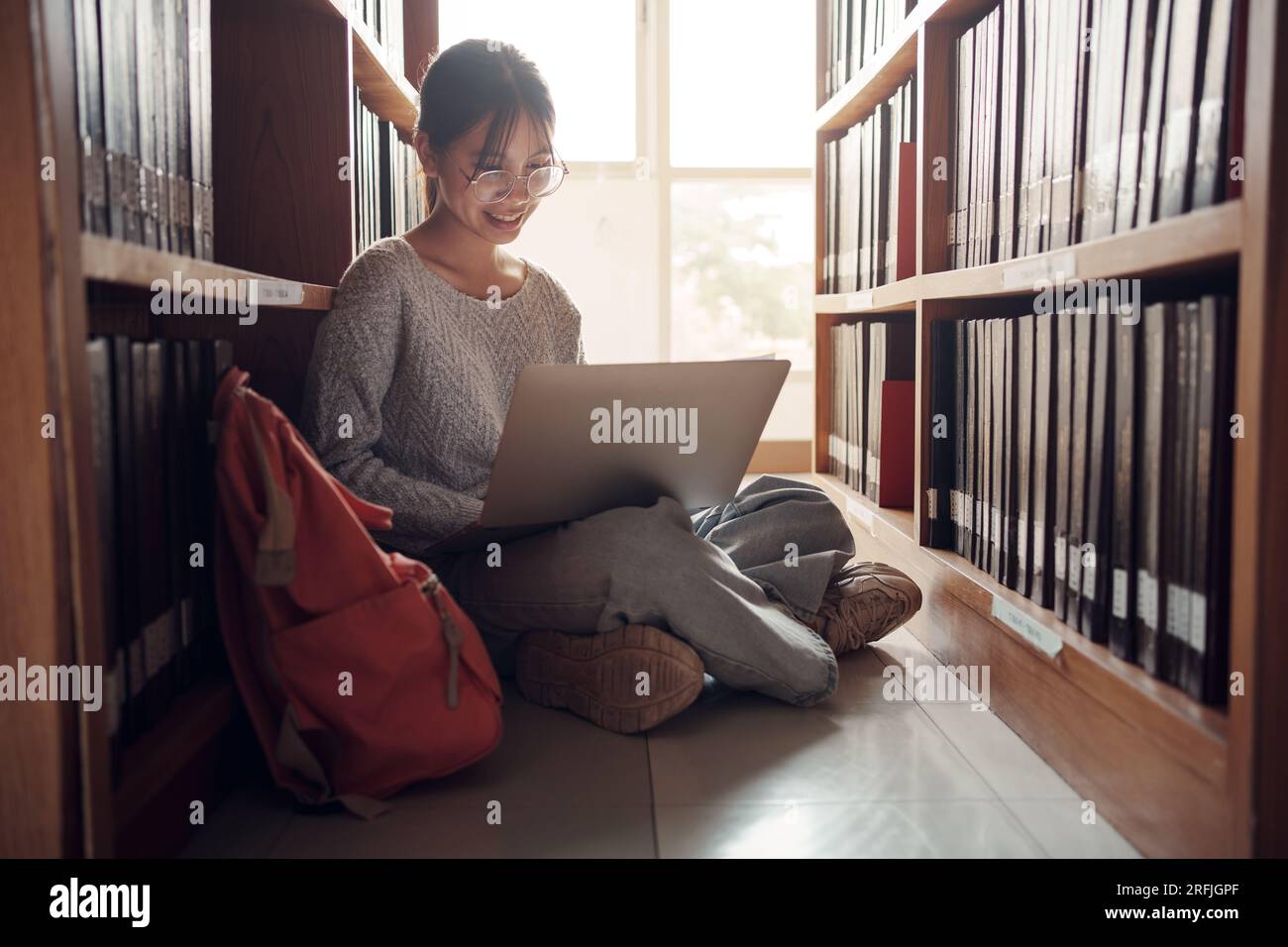 Studentessa seduta sul pavimento e che utilizza il laptop, scrive note per la carta, saggio, studio per l'assegnazione della classe. Gruppo eterogeneo di studenti che imparano, Studyin Foto Stock