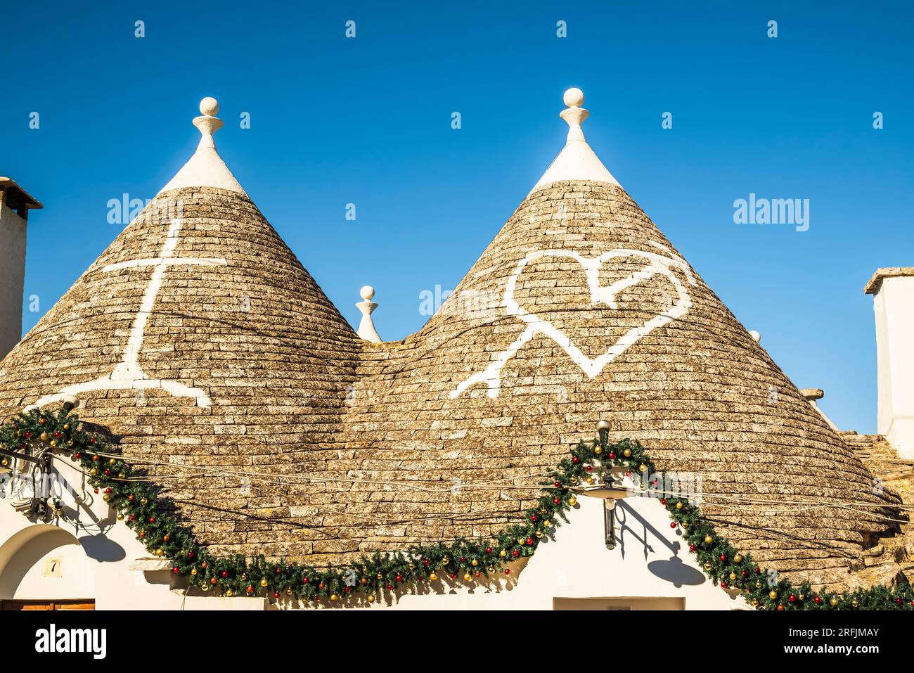 Alberobello, Italia - 1 gennaio 2023: Simboli di un cuore trafugato da una freccia raffigurante Santa Maria Addolorata dipinta sul tetto dei trulli Foto Stock