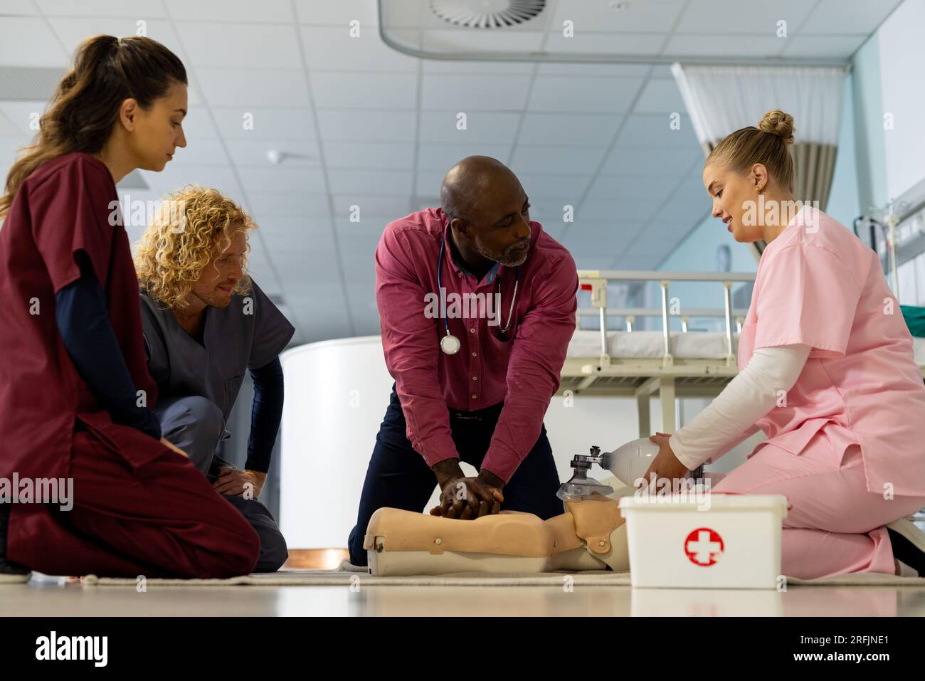 Senior afroamericano medico maschile con diversi medici tirocinanti che imparano rcp su modello in ospedale Foto Stock