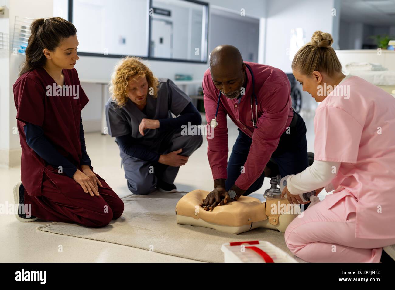 Senior afroamericano medico maschile con diversi medici tirocinanti che imparano rcp su modello in ospedale Foto Stock