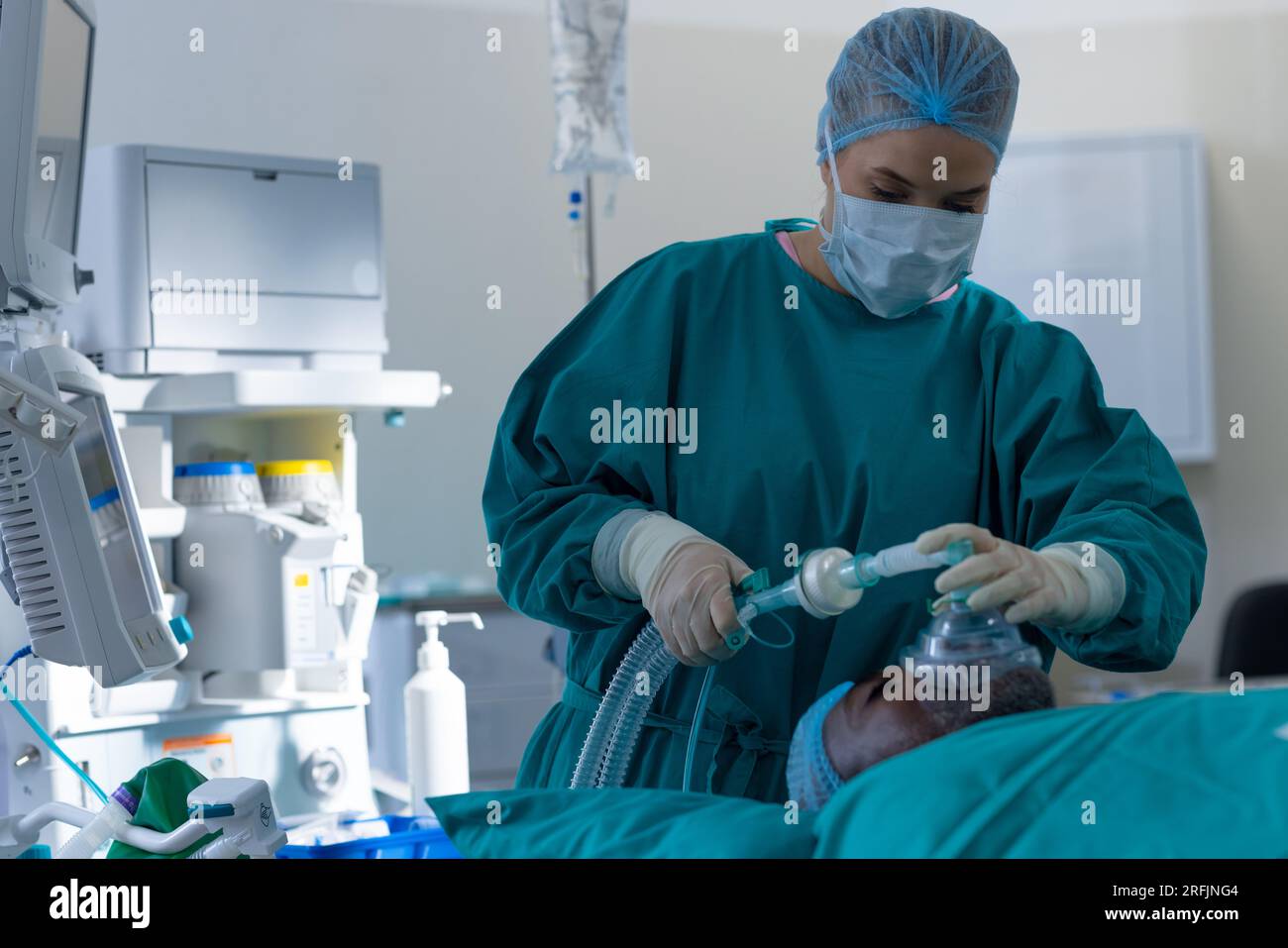 Chirurgo femminile caucasico ponendo maschera anestetica sul paziente in sala operatoria in ospedale Foto Stock
