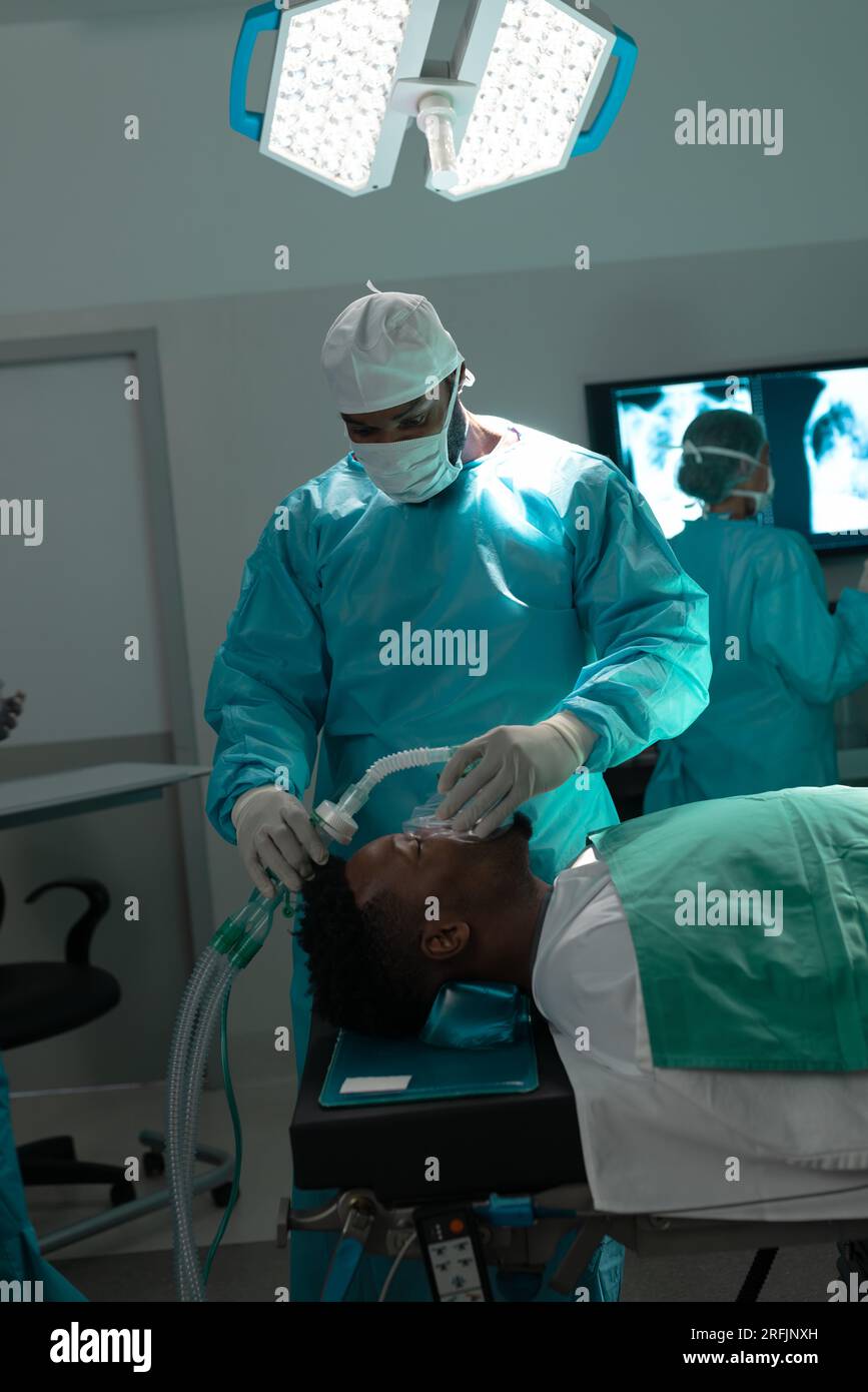 Chirurgo afro-americano che pone la maschera anestetica sul paziente in sala operatoria all'ospedale Foto Stock