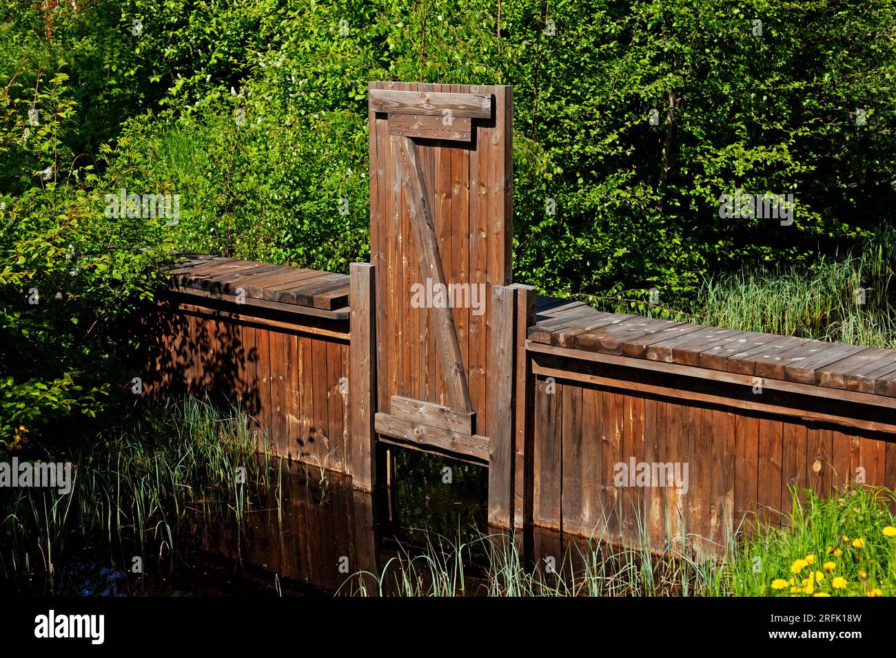 una vecchia diga di legno e un piccolo torrente Foto Stock