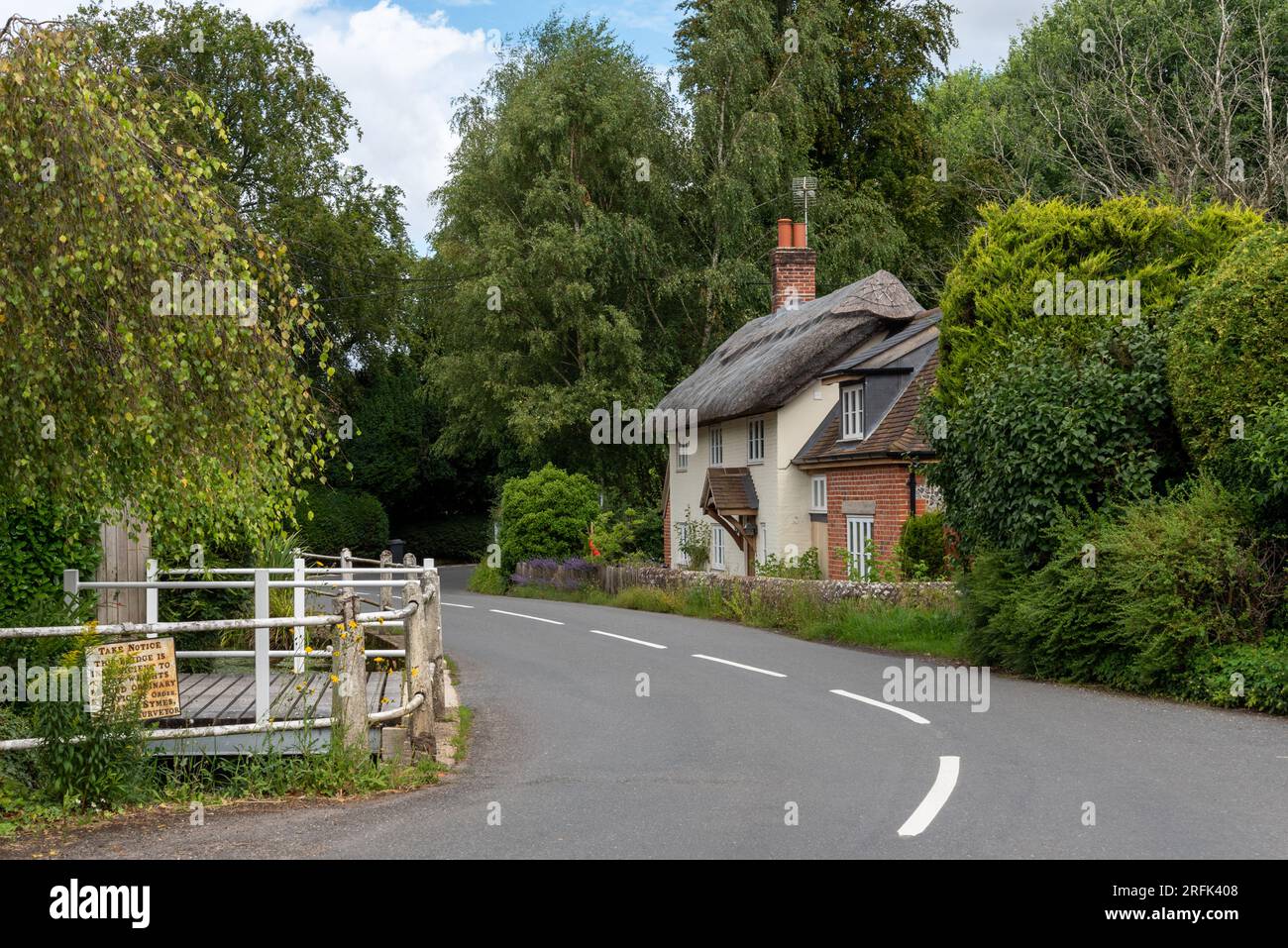 Tranquillo scenario rurale con una strada tortuosa e una casa di paglia circondata da alberi nel villaggio di Cheriton nell'Hampshire, Inghilterra. Agosto 2023. Foto Stock