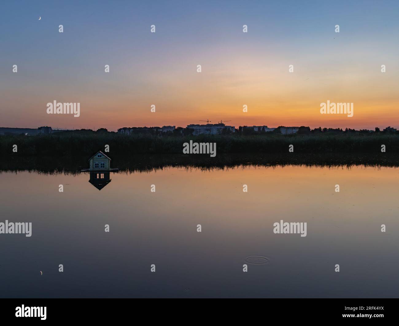Incredibile riflesso di un cielo blu arancione in un lago in un parco al tramonto Foto Stock