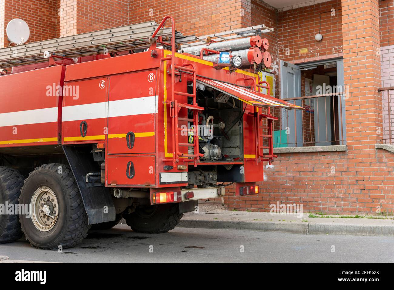 un camion dei pompieri con una sirena a richiesta nel cortile della città. luci blu e sirene su un camion dei pompieri. Autocarro antincendio con luci lampeggianti, pronto per lo smontaggio Foto Stock
