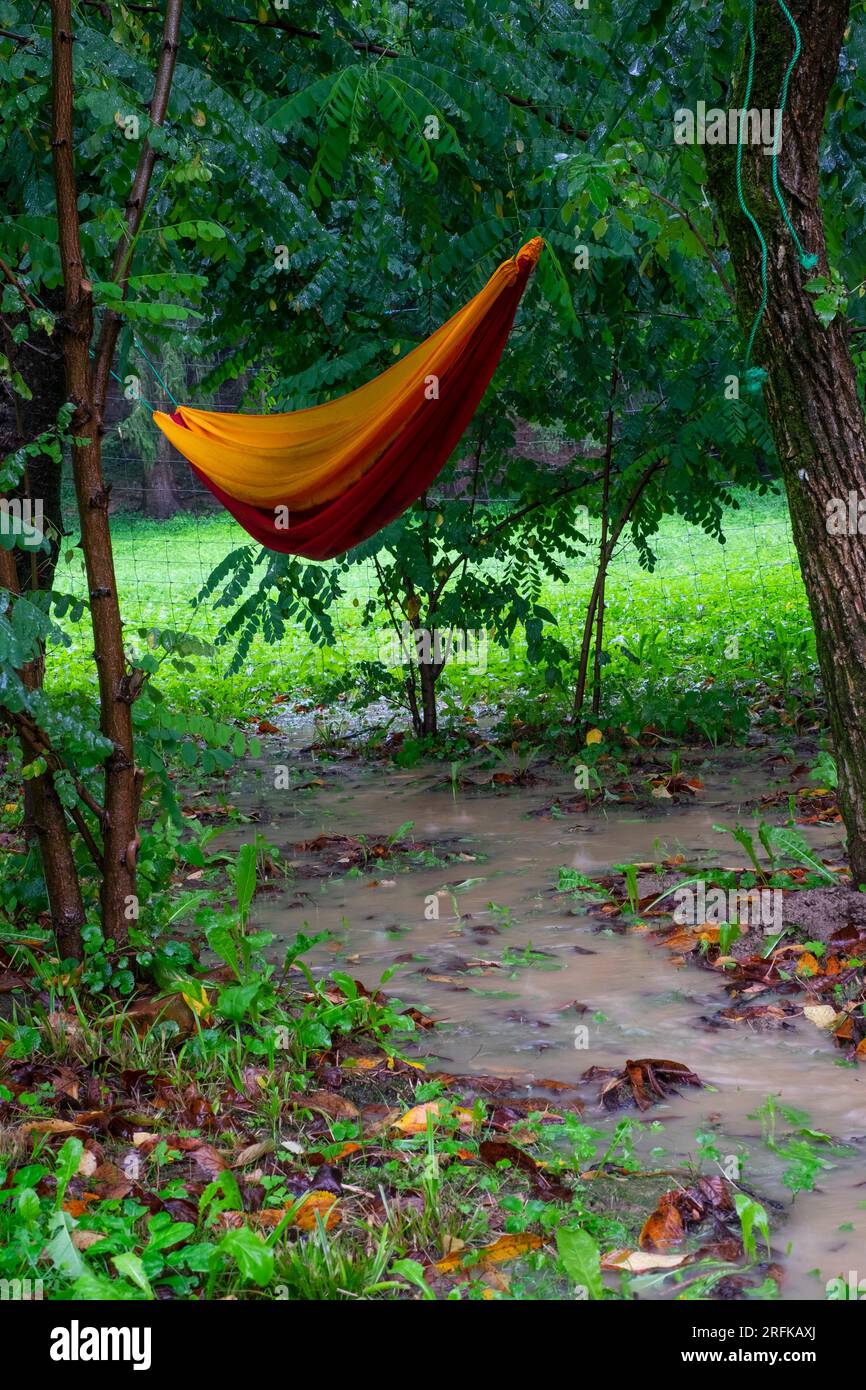 amaca bagnata appesa a forza in un giardino inondato di pioggia sopra il fiume d'acqua, simbolo della tipica contea estiva di zala in ungheria Foto Stock