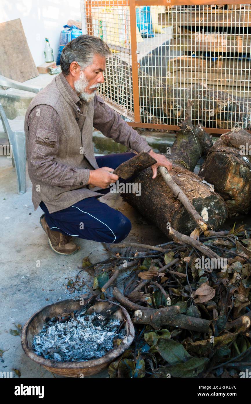 14 ott.2022 Uttarakhand, India. Uomo anziano che usa un'ascia per tagliare tronchi di legno in piccoli pezzi per la legna da ardere nel suo cortile. Taglio tradizionale a legna Foto Stock