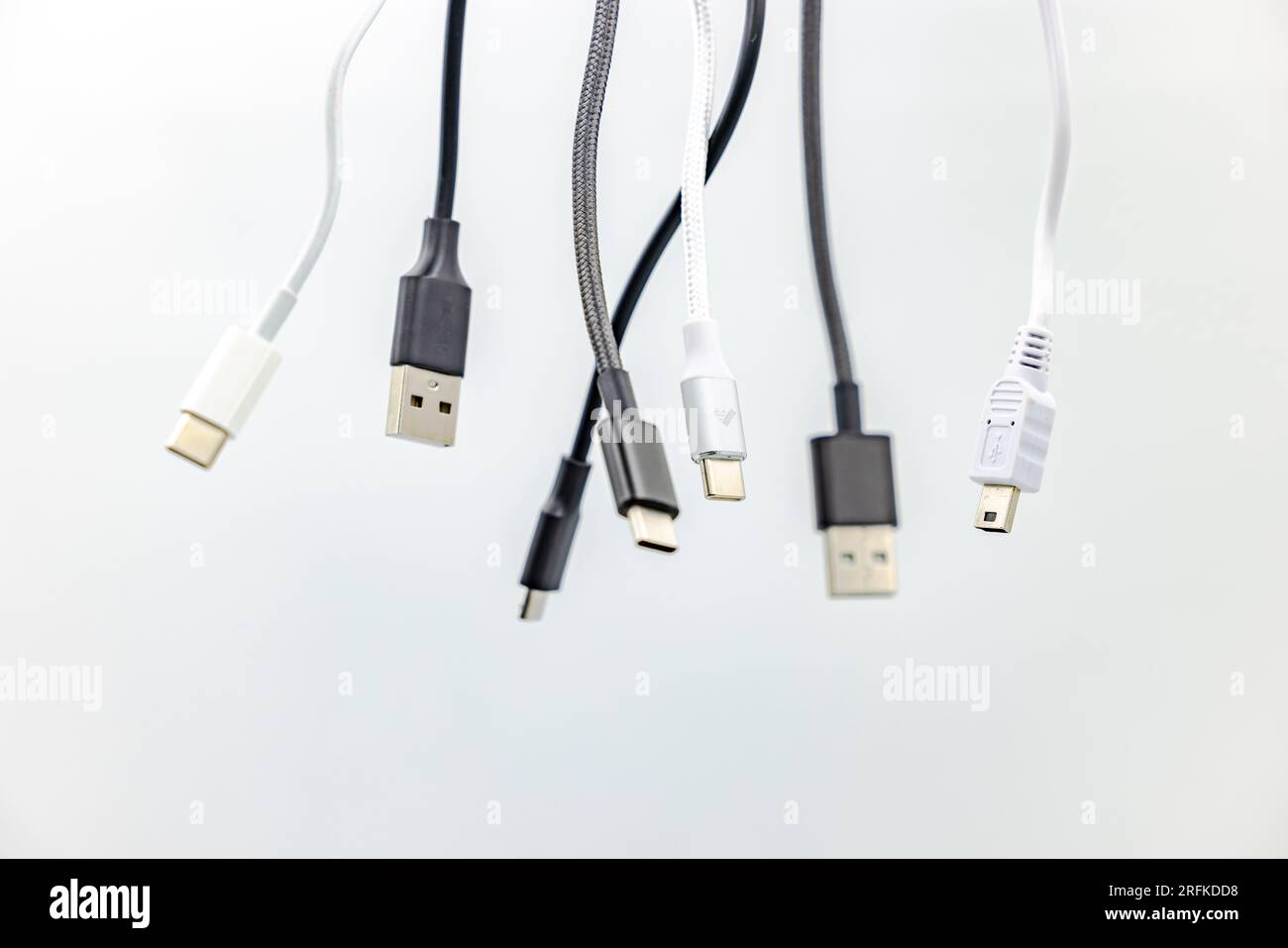 Vari cavi e connettori USB di tipo A e C in bianco e nero tagliati in studio su sfondo bianco Foto Stock
