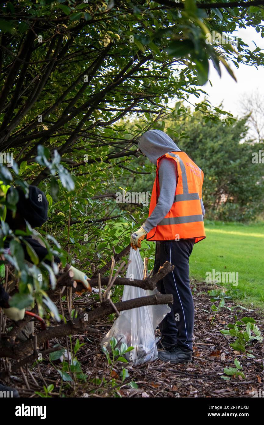 I sacchetti di plastica pieni di rifiuti vengono rimossi dai terreni di un centro sportivo dal team Community Payback. Foto Stock