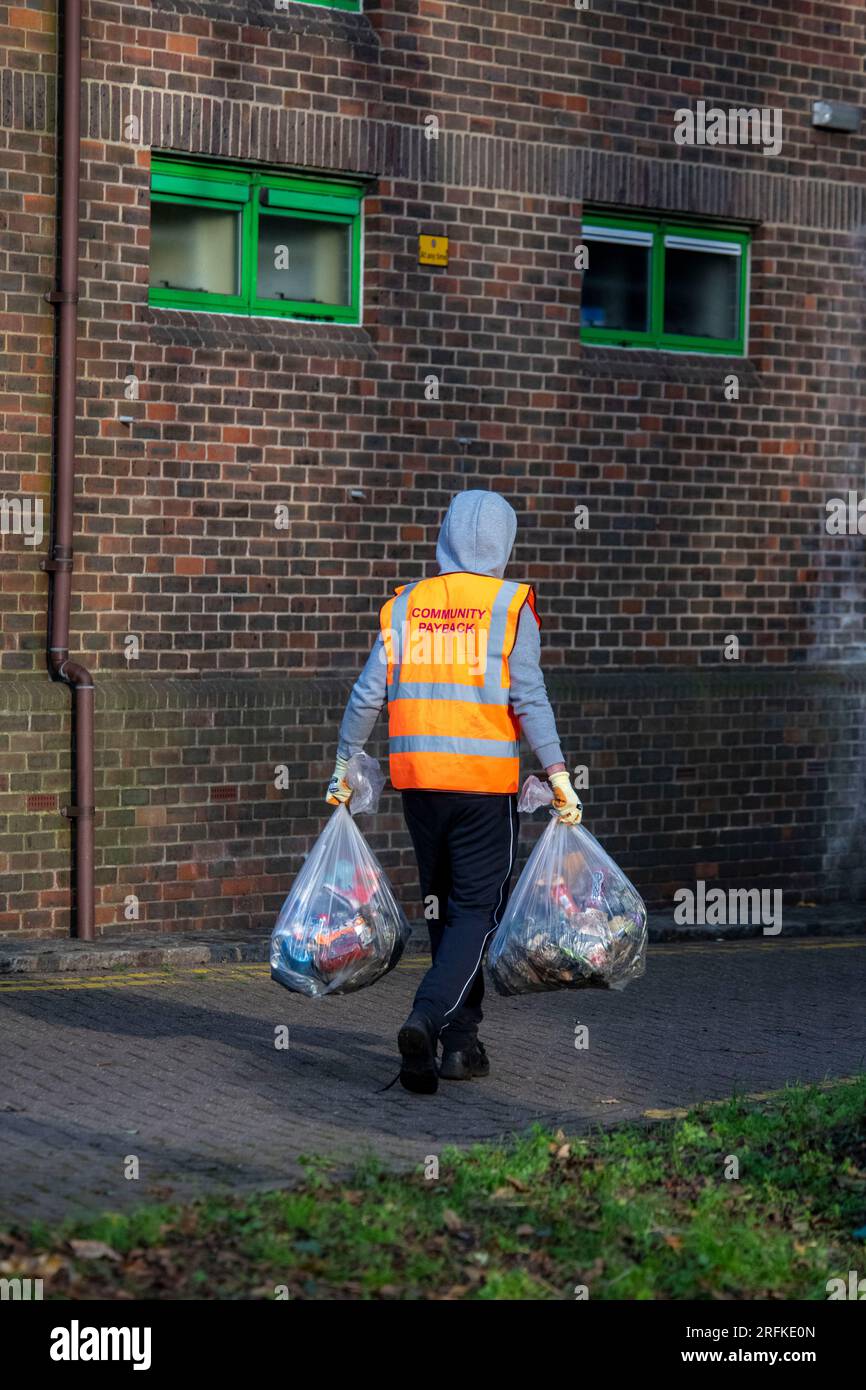 I sacchetti di plastica pieni di rifiuti vengono rimossi dai terreni di un centro sportivo dal team Community Payback. Foto Stock