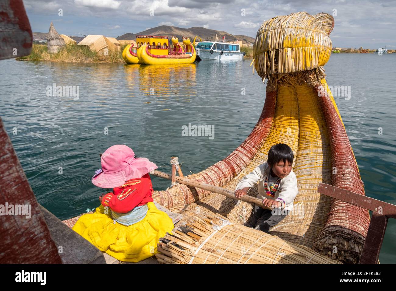 I bambini piccoli, appartenenti agli Uros, navigano sul lago Titicaca Foto Stock