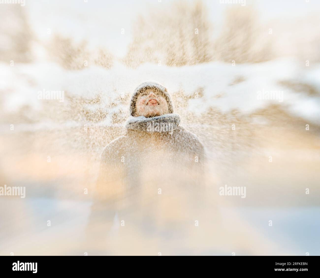 ragazzo che lancia e cattura la neve nell'aria in una scena invernale Foto Stock