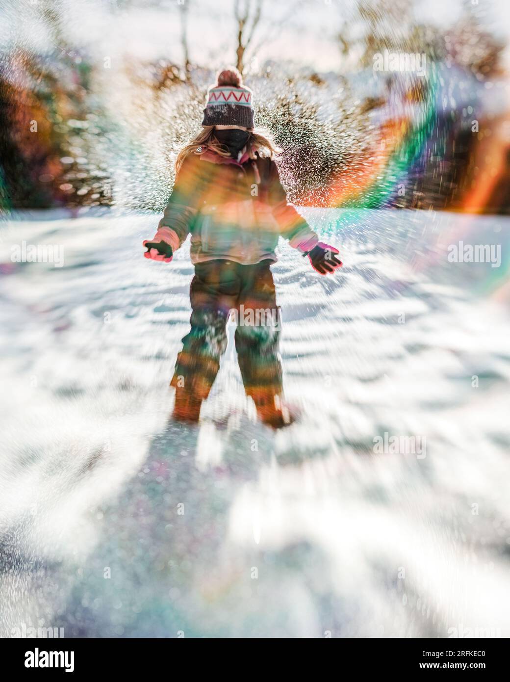 bambina di 8 anni che lancia neve in aria in una scena invernale nel cortile Foto Stock