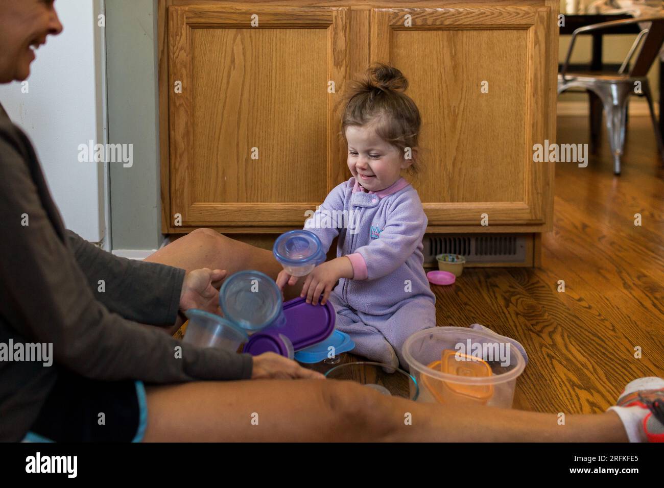 bimba che gioca con piatti di plastica in cucina Foto Stock