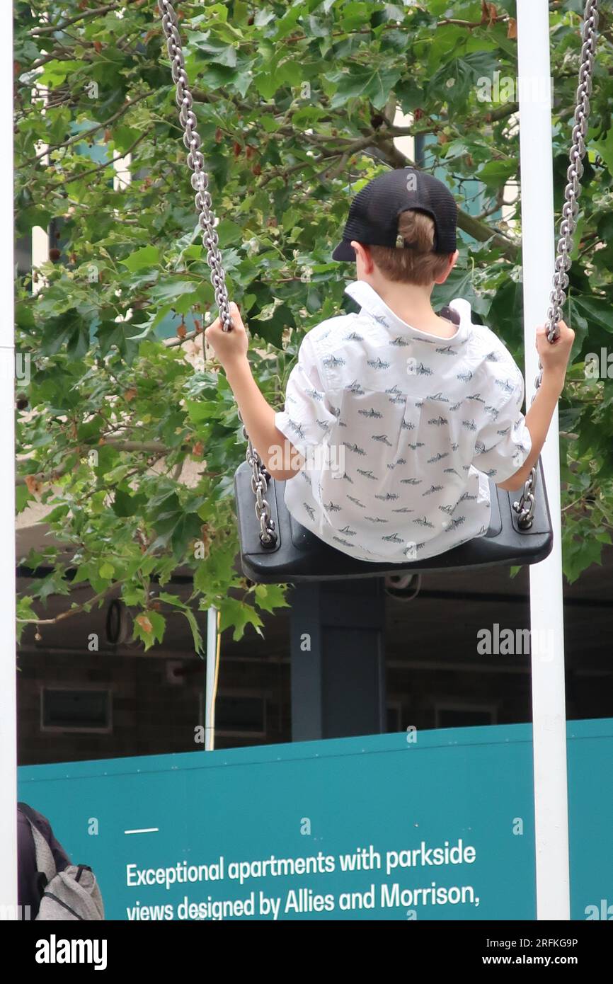 Il giovane ama l'altalena che si trova nel mezzo della "Bird Cage", un'installazione artistica a Battle Bridge Place, la vivace piazza di King's Cross. Foto Stock