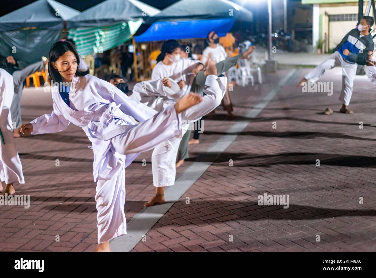 Dumaguete, Isola di Negros, Filippine-gennaio 29 2023: Molte studentesse di Karate filippine sicure di sé, in uniforme, si allenano regolarmente la sera, in un pub Foto Stock