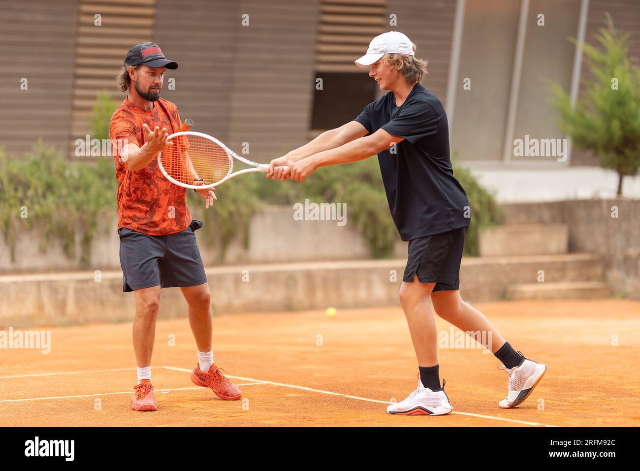 Padre insegna a suo figlio a giocare a tennis sul campo. Scatto medio Foto Stock