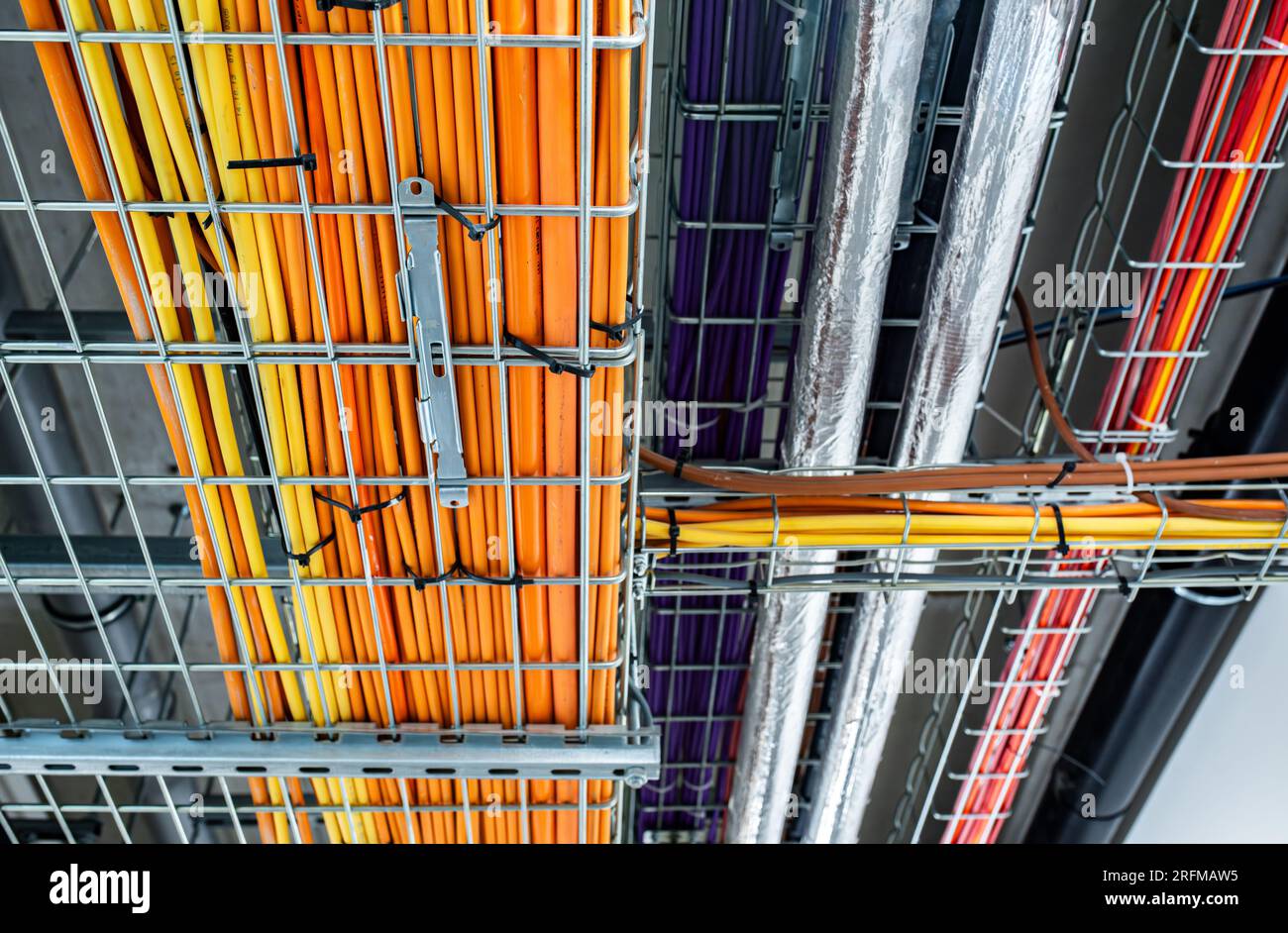 Sistema di condotti elettrici e condutture metalliche installati sul soffitto dell'edificio, cavi colorati, concetto di power House Foto Stock