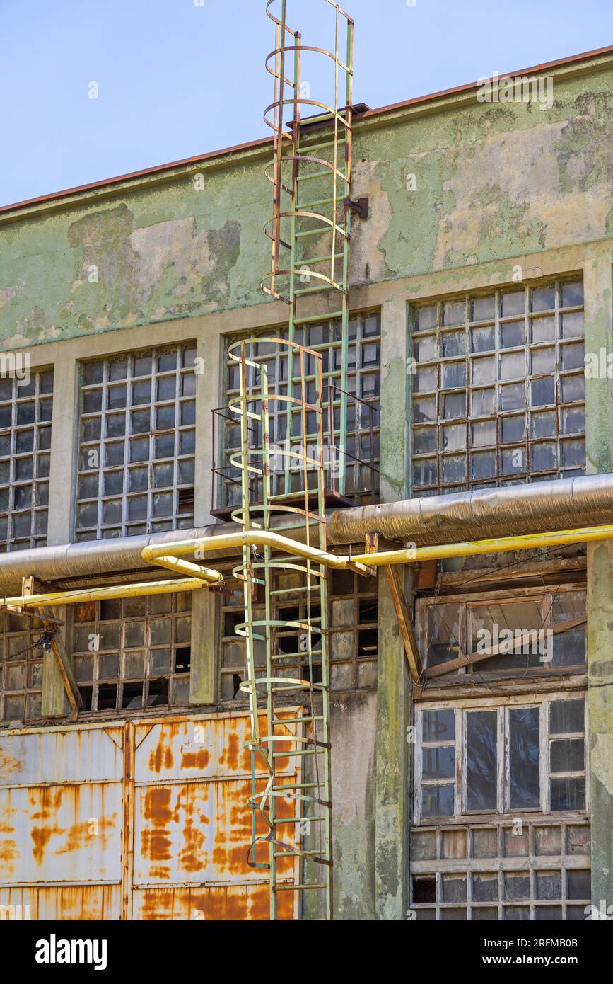 Scale verticali con gabbia di sicurezza all'esterno dell'edificio industriale Rusty Old Abandon Foto Stock