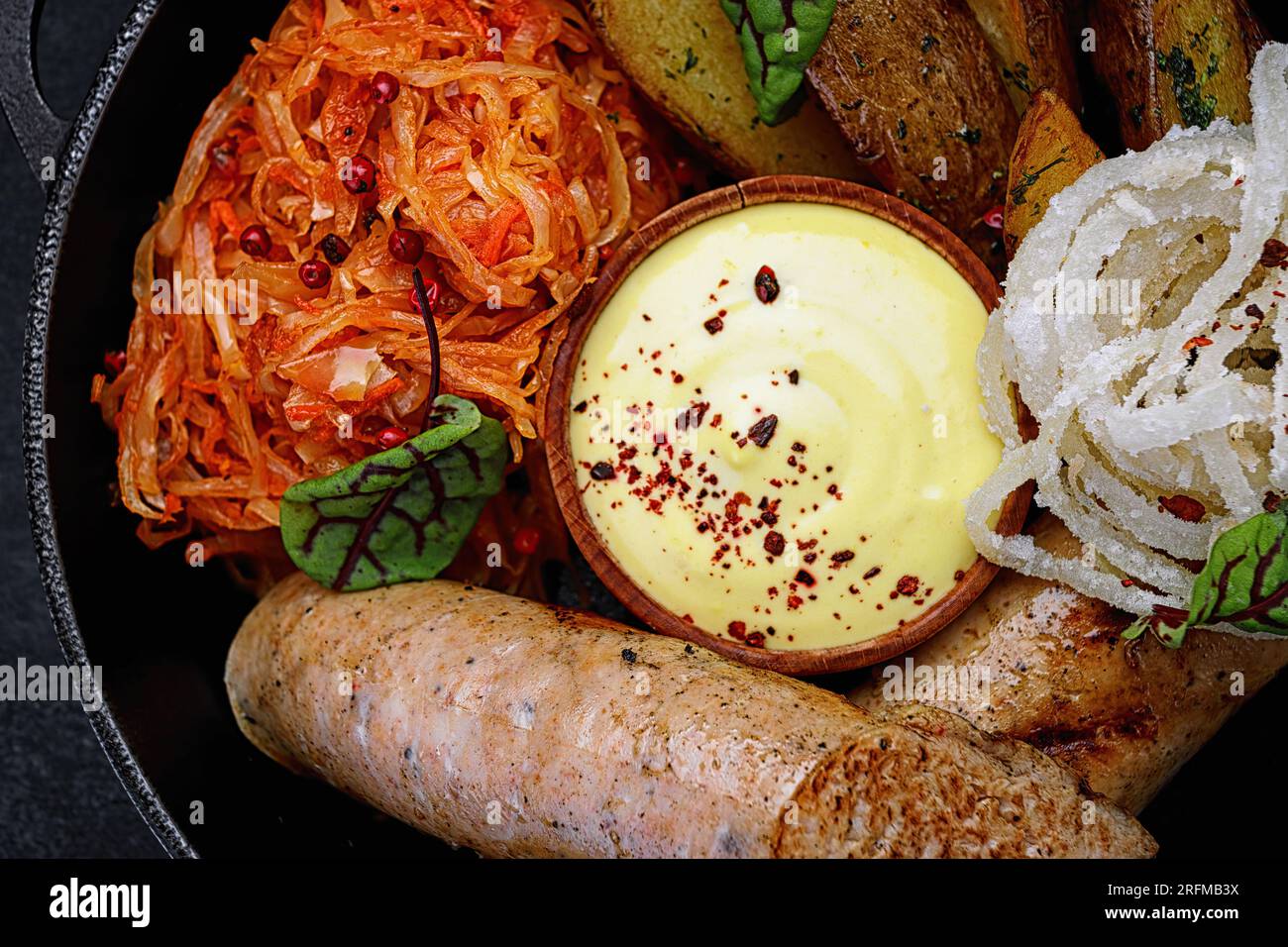Salsicce fritte con patate al forno, cavolo stufato, in padella. primo piano Foto Stock