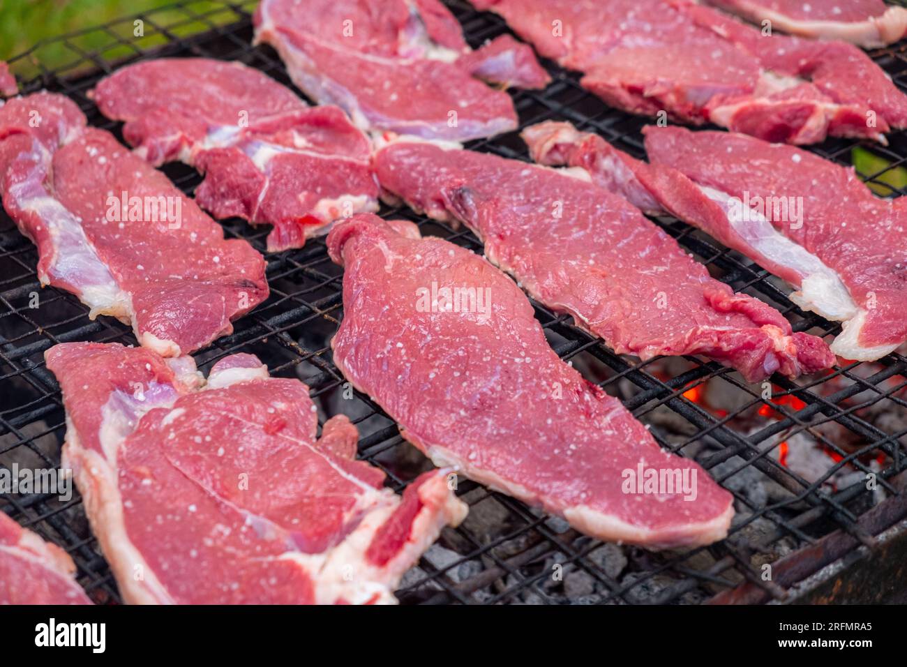pezzi di manzo crudo preparati per la tostatura su una griglia a carbone Foto Stock