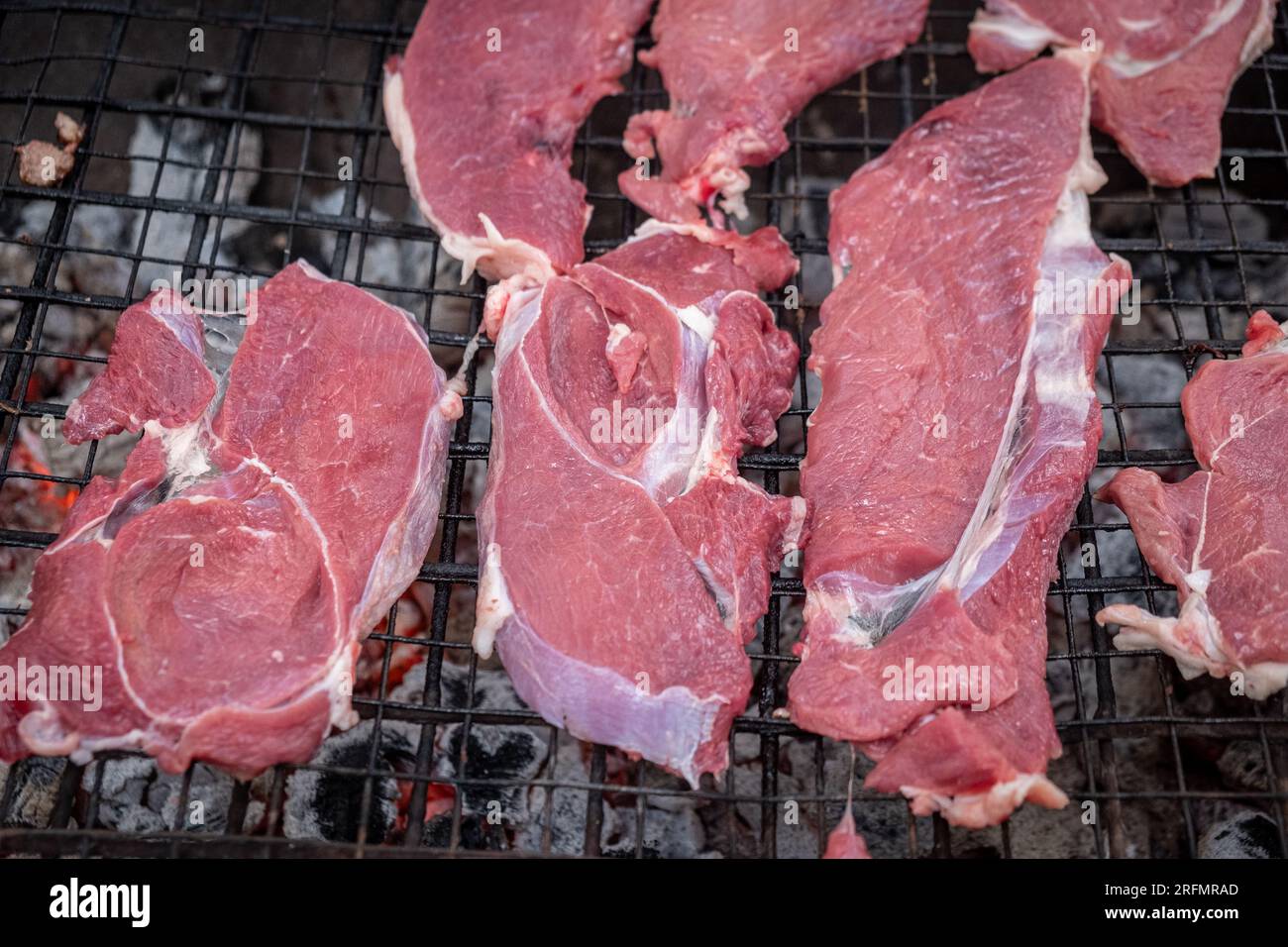 pezzi di manzo crudo preparati per la tostatura su una griglia a carbone Foto Stock