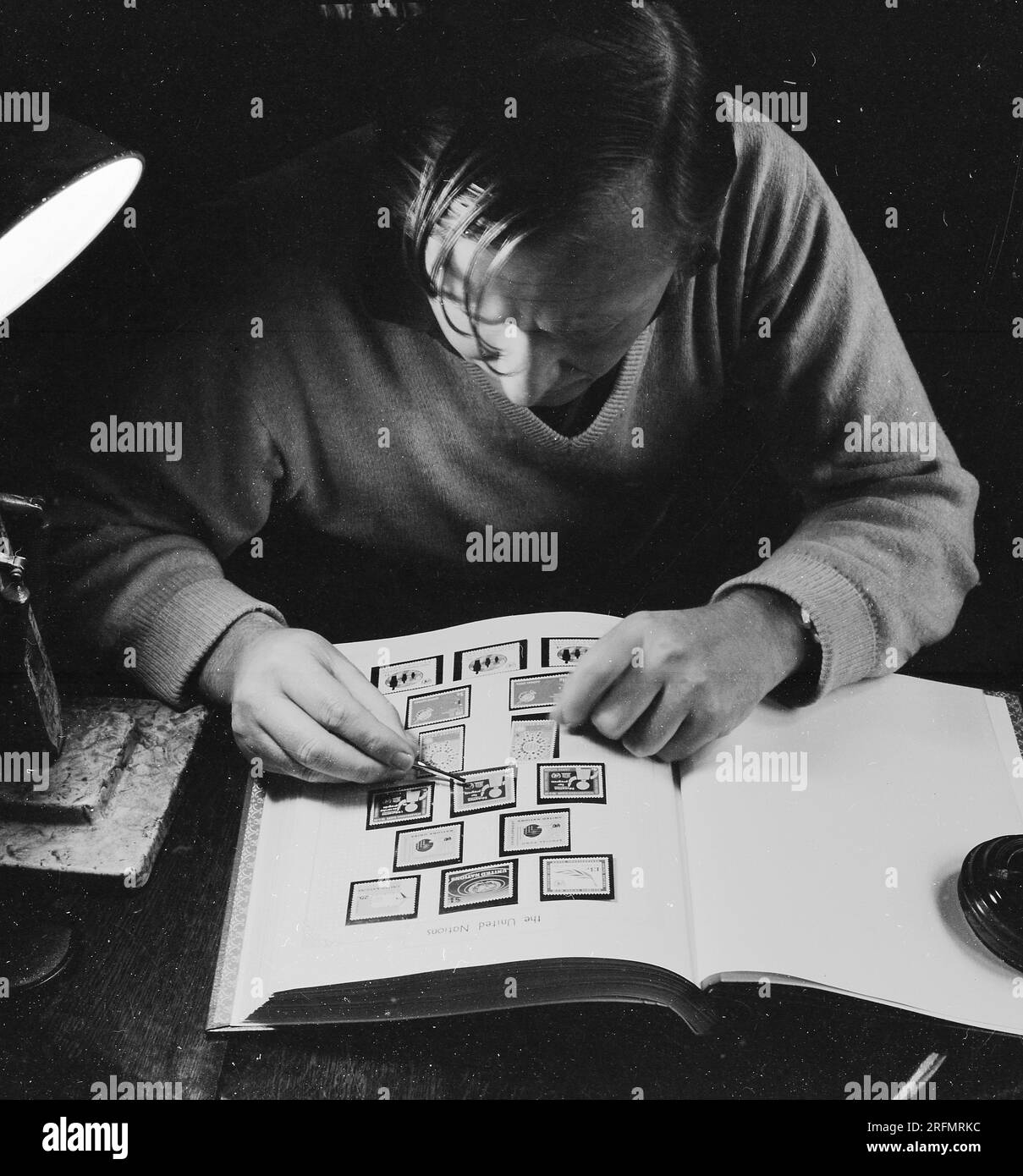 1969, storico, un uomo che mette con attenzione un timbro nel suo album di francobolli su una pagina intitolata, le Nazioni Unite, Inghilterra, Regno Unito. Foto Stock