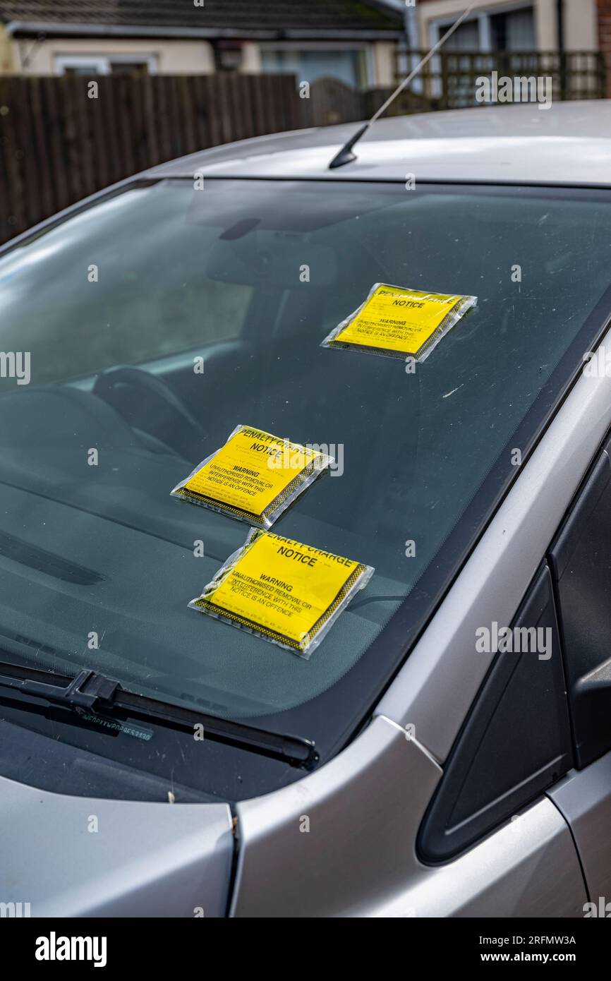Biglietti multipli per il parcheggio o avvisi di penalità sul parabrezza di un'auto parcheggiata in strada Foto Stock