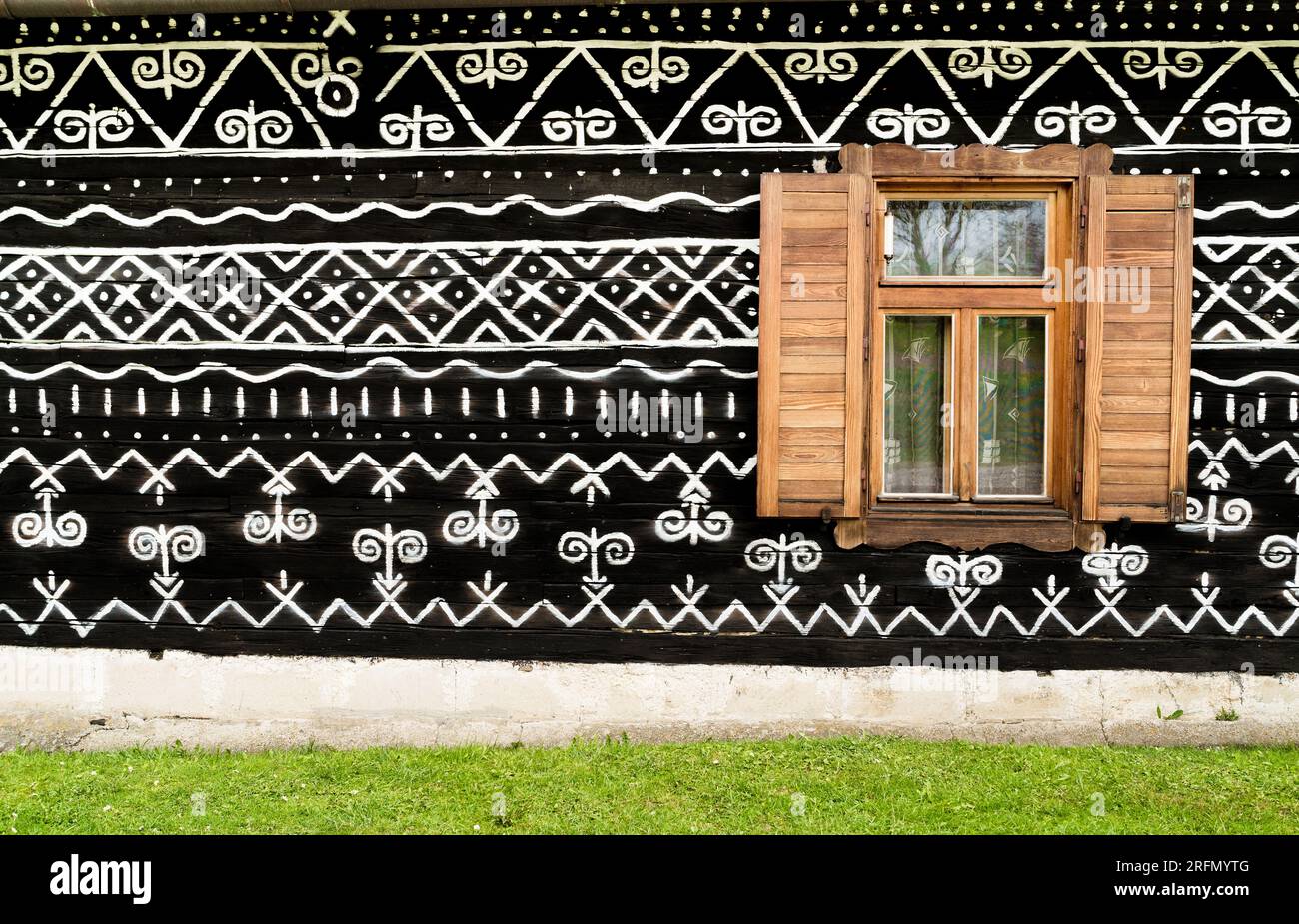 Finestra in legno sul dipinto ornamentale con motivi bianchi e neri sulle pareti in legno scuro nel vecchio villaggio slovacco di Cicmany. Patrimonio storico europeo e b Foto Stock