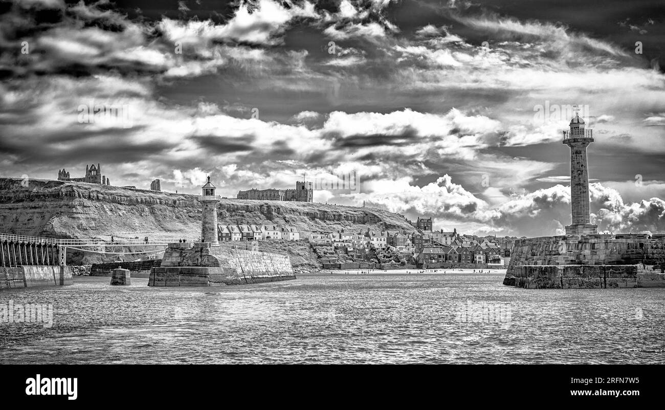 Un panorama di Whitby dal mare. Un paio di fari sorvegliano l'ingresso di un porto. L'abbazia e una chiesa sono sulla scogliera e la gente è su un Foto Stock