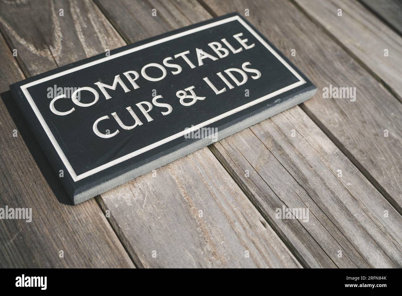 Un cartello su un apposito contenitore di riciclaggio che accetta tazze da caffè compostabili e coperchi con spazio per le copie Foto Stock