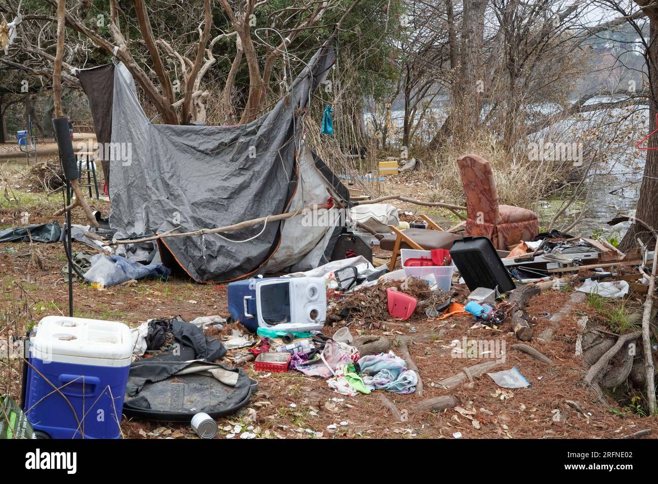 Austin Texas USA, 2 gennaio 2023: Spazzatura e oggetti personali di un campo da senzatetto lungo la riva nord del lago Lady Bird vicino a Rainey Street nel centro di Austin. I funzionari della città stanno lottando con problemi di senzatetto lungo le popolari escursioni a piedi e in bicicletta nel parco pubblico che circonda il lago. ©Bob Daemmrich Foto Stock