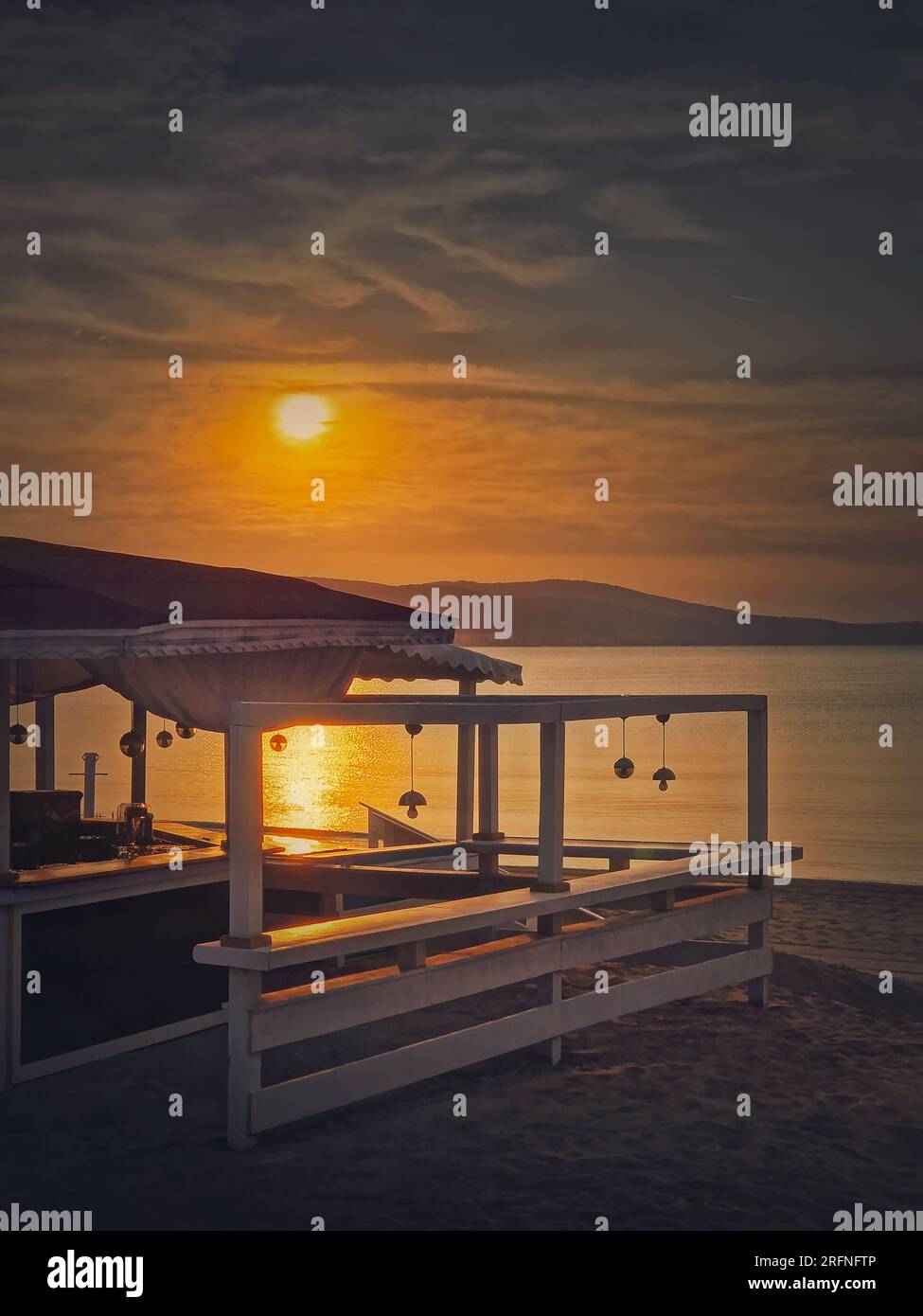 La mattina presto sul mare accanto al bar della spiaggia con una splendida vista dell'alba sul mare. Concetto di vacanza e relax Foto Stock